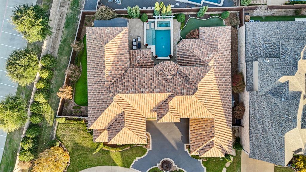 Aerial perspective of a multi-gabled tile roof residence featuring a swimming pool, attached spa, putting green, and stone-surfaced patio area
