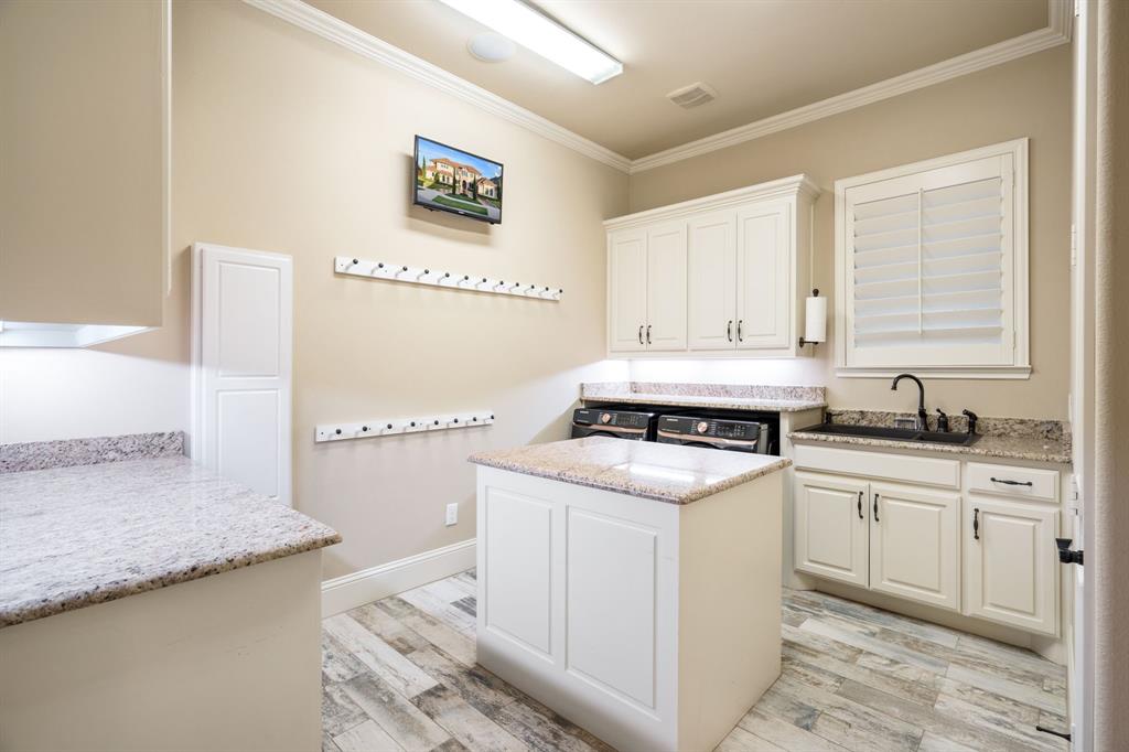 Utility room featuring white cabinetry, stone-finish countertops, a center island with prep space, an undermount sink with a matte black faucet, and wood-finish flooring