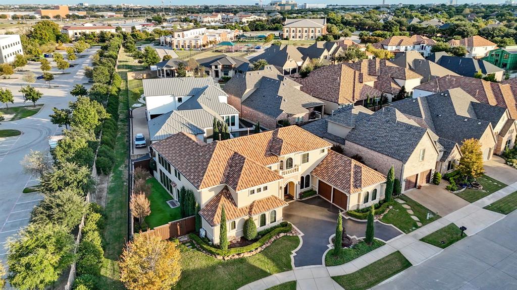 Two-story residential structure featuring a clay tile roof, arched entryway, upper-level balcony, and attached multi-car garage with a paved driveway