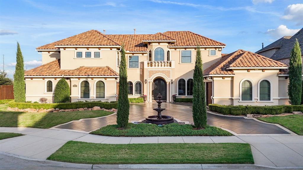 Mediterranean-style exterior featuring a stucco facade, tile roof, arched windows, grand gated entry, and a decorative fountain