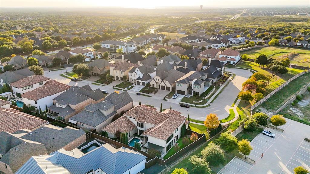 Aerial perspective of a suburban neighborhood featuring residential homes, multi-gabled rooflines, stone and stucco facades, and a private swimming pool