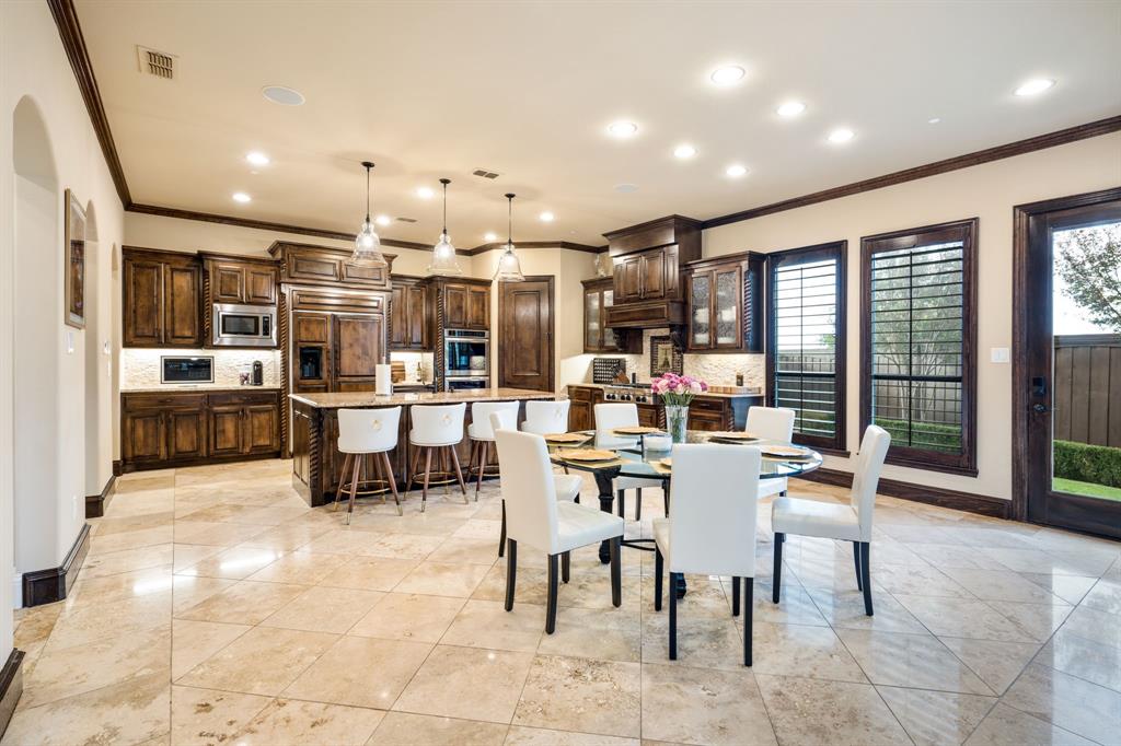Kitchen featuring dark wood cabinetry, a central island with stone-finish countertops, tile flooring, recessed lighting, and pendant illumination