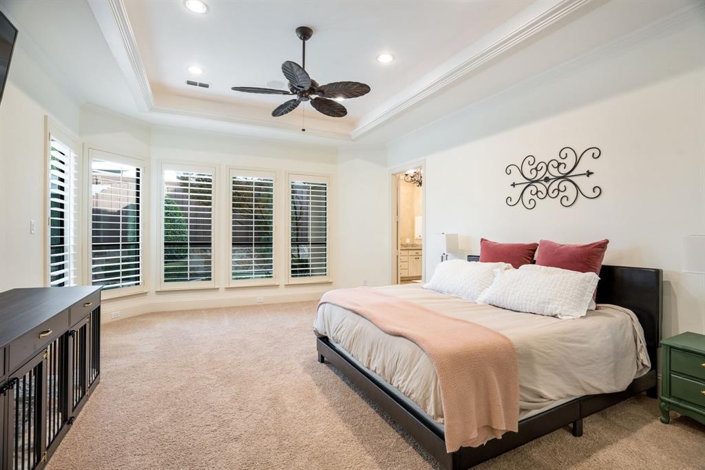 Tray ceiling with recessed lighting, ceiling fan, carpeted flooring, and plantation shutters on multi-pane windows