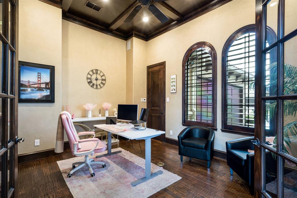 Rich wood-finish flooring, high coffered ceiling with dark wood detailing, arched dual-pane windows, and solid wood French entry doors