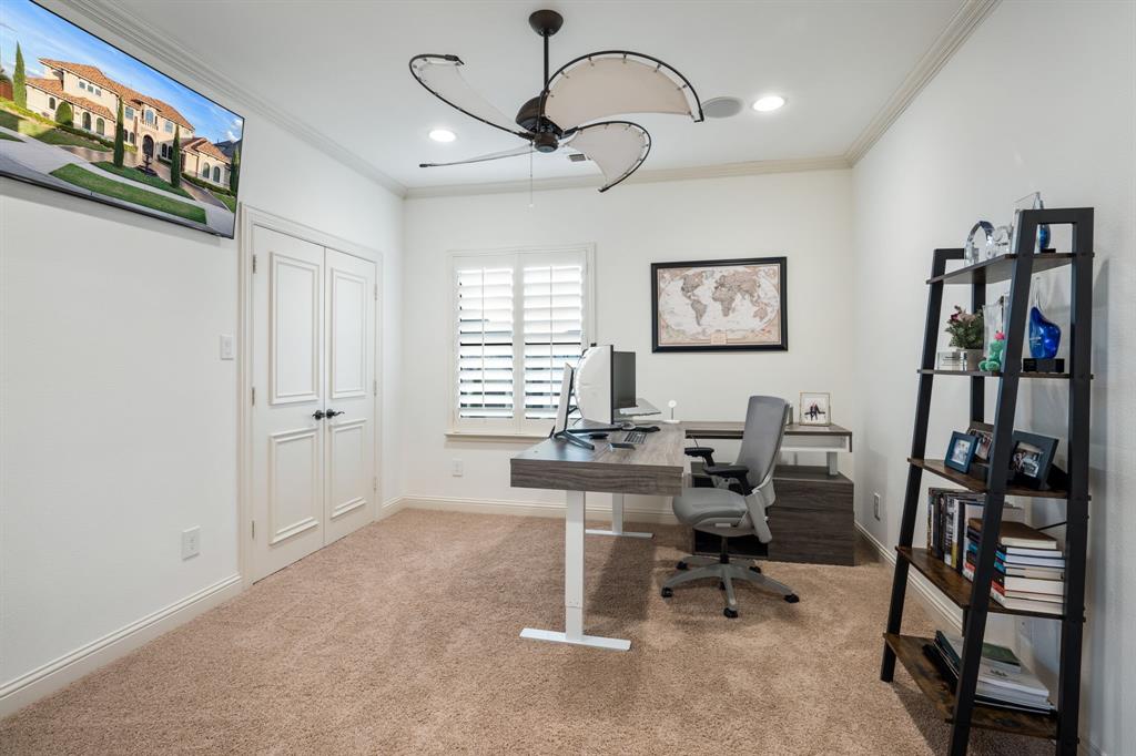 Room featuring plush wall-to-wall carpeting, crown molding, double doors, window plantation shutters, and a multi-blade ceiling fan with integrated lighting