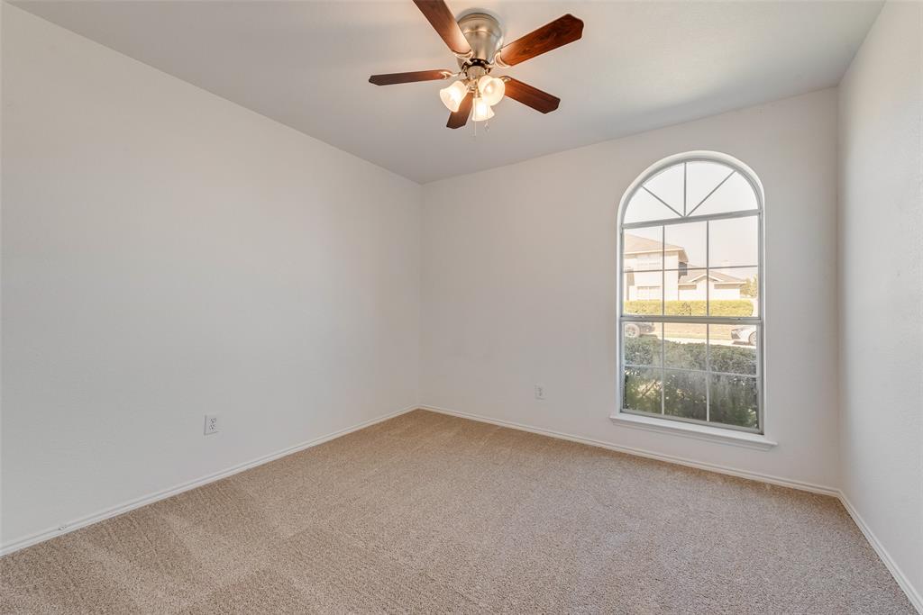 Neutral-toned wall finish, wall-to-wall carpeting, arched window with a grid pattern, and a ceiling-mounted fan with integrated lighting