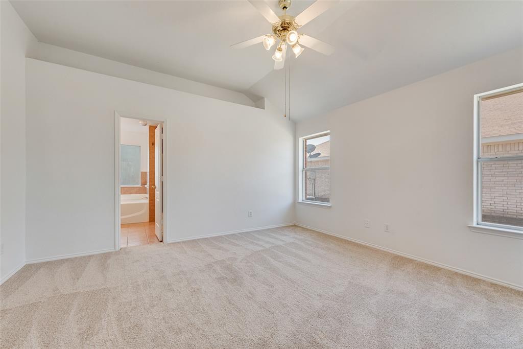 Interior space featuring vaulted ceilings, neutral wall-to-wall carpeting, and a multi-light ceiling fan