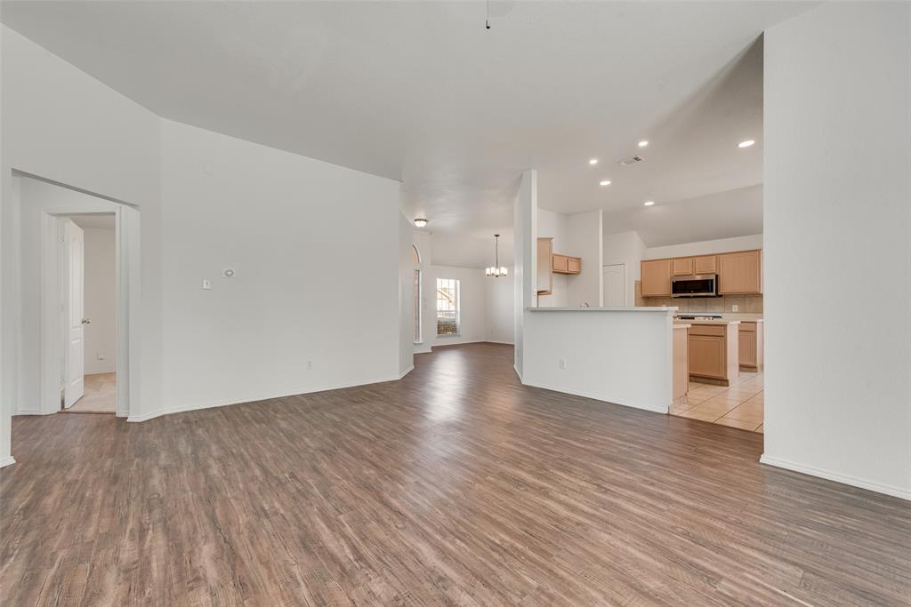 Open floor plan featuring wood-finish flooring, recessed lighting, a breakfast bar, and cabinetry with integrated appliances Open floor plan featuring wood-finish flooring, recessed lighting, a breakfast bar, and cabinetry with integrated appliances