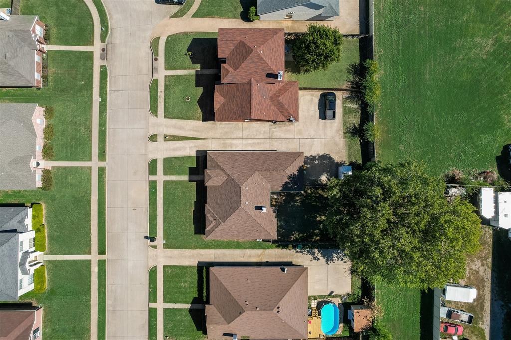 Aerial perspective featuring a residential lot with a concrete driveway and an inground swimming pool Aerial perspective featuring a residential lot with a concrete driveway and an inground swimming pool