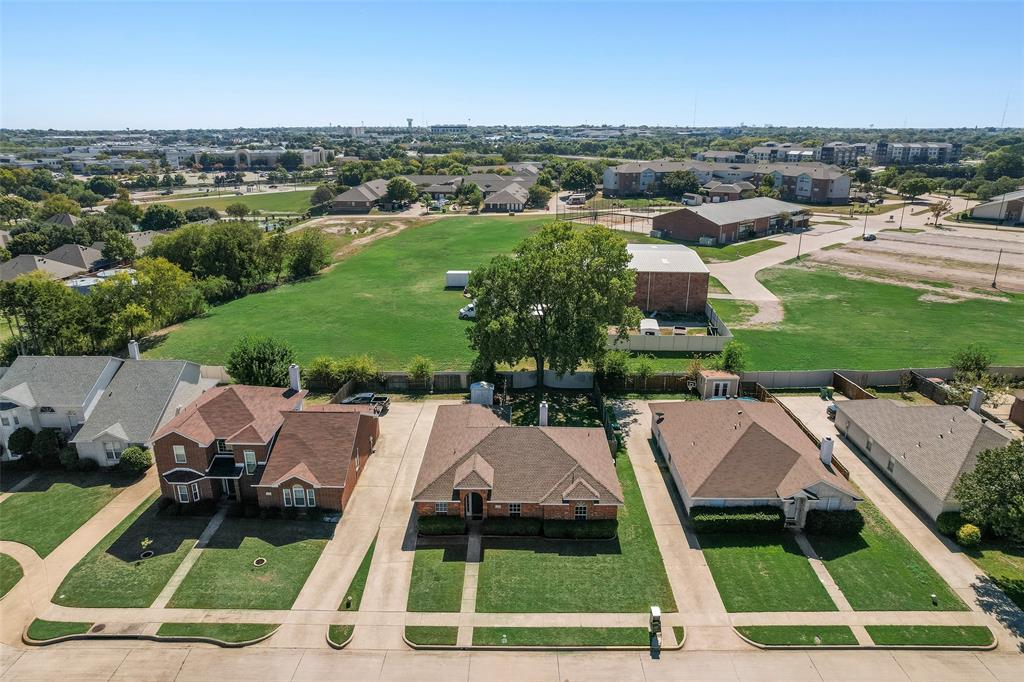 Aerial perspective of a suburban neighborhood featuring brick-exterior single-story and two-story homes, expansive rear lot space, mature trees, and paved driveways Aerial perspective of a suburban neighborhood featuring brick-exterior single-story and two-story homes, expansive rear lot space, mature trees, and paved driveways