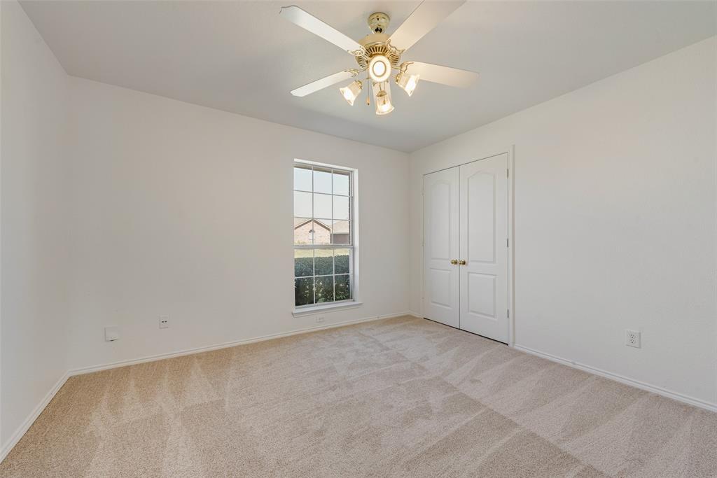 Neutral-toned carpeted flooring, multi-pane window, ceiling fan with integrated lighting, and double-panel doors