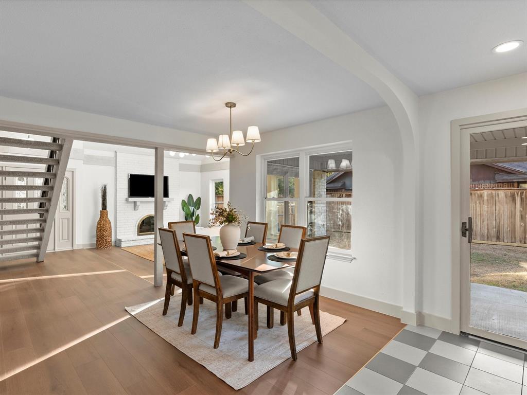 Dining area featuring wood-finish flooring, arched architectural detailing, a multi-light chandelier, and a glass-paned sliding door