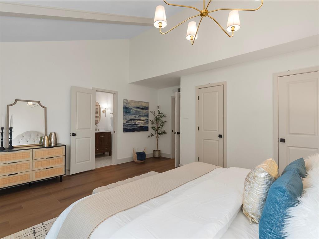 Vaulted ceilings, wood-finish flooring, multi-arm metallic chandelier, and two-panel doors with matte black hardware