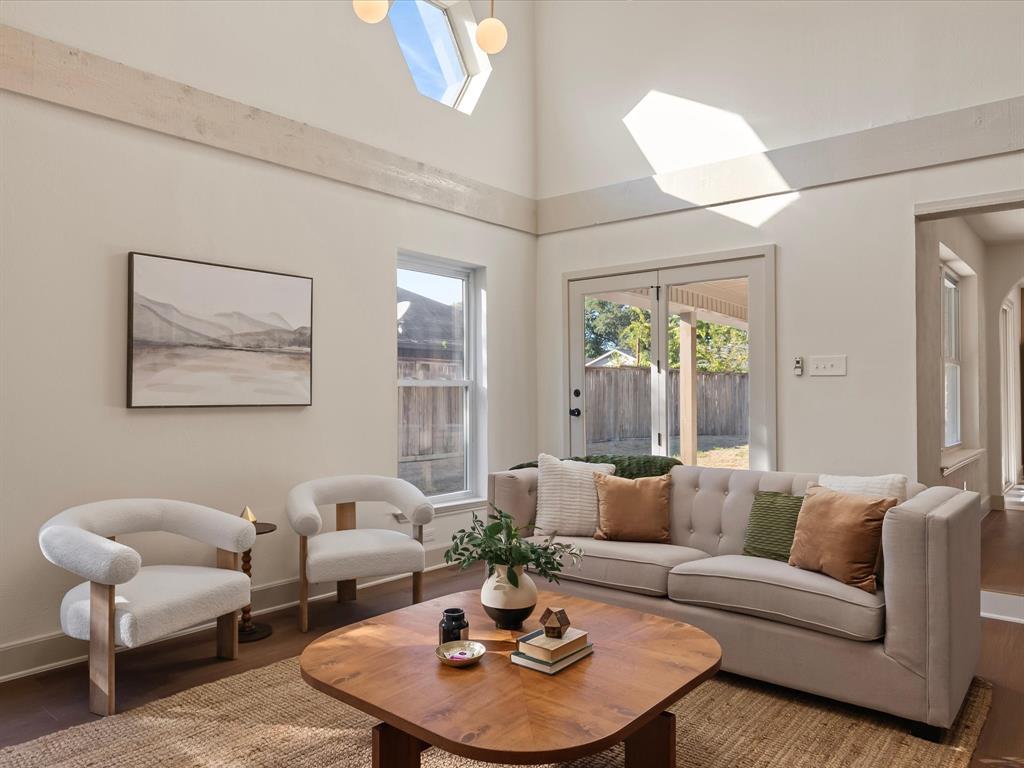Vaulted ceilings featuring horizontal wood beam detailing, geometric transom window, wood-finish flooring, and double-pane glass entry doors