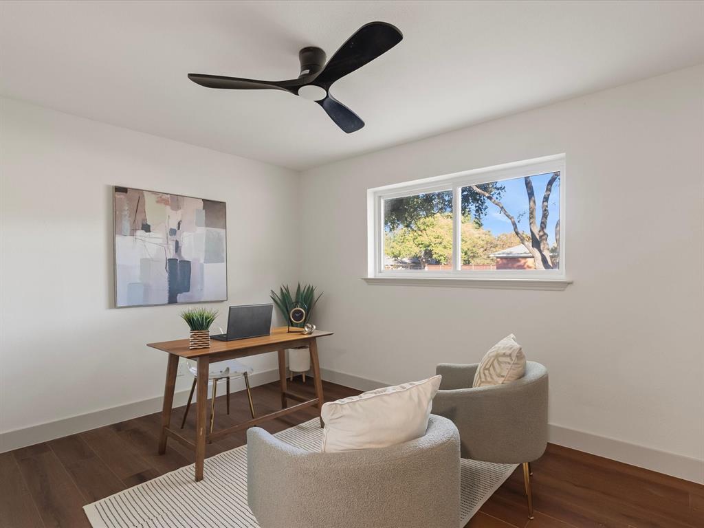 Room featuring wood-finish flooring, a modern three-blade ceiling fan, and a large horizontal sliding window