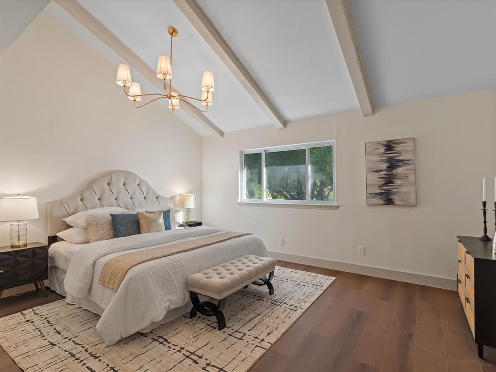Vaulted ceiling featuring exposed beams, wood-finish flooring, and a multi-arm chandelier