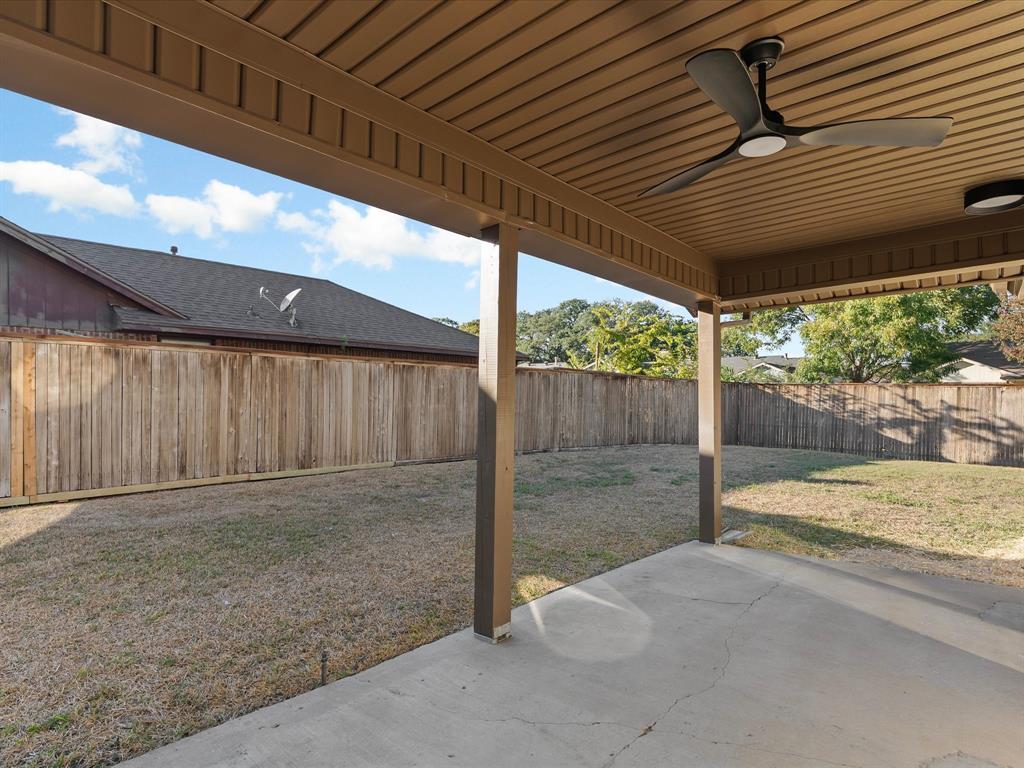 Covered concrete patio featuring a ceiling-mounted fan and fenced backyard