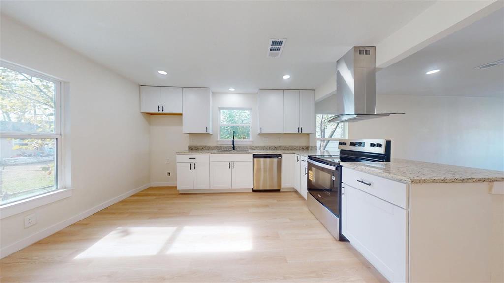 Kitchen featuring white shaker-style cabinetry, stone-finish countertops, stainless steel appliances, a stainless steel range hood, and wood-finish flooring