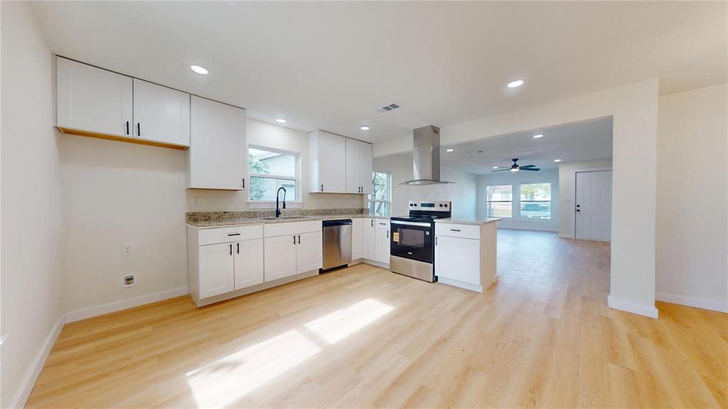 Kitchen featuring white cabinetry, stone countertops, stainless steel appliances, a stainless steel chimney-style range hood, and wood-finish flooring