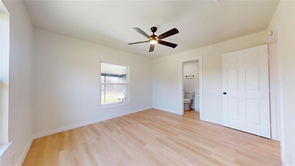 Interior space featuring light-toned wood-finish flooring, a multi-blade ceiling fan with integrated lighting, and a six-panel door