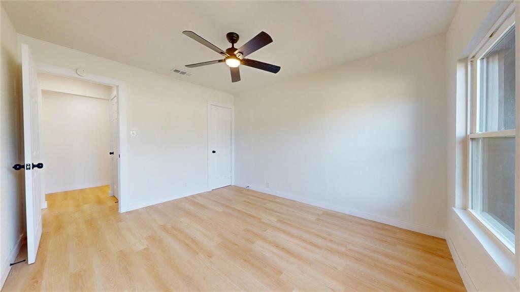 Neutral-toned interior featuring wood-finish flooring, a five-blade ceiling fan, multi-panel doors, and a double-hung window