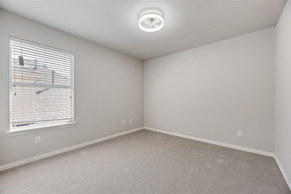 Neutral-toned interior space featuring wall-to-wall carpeting, a single-pane window with horizontal blinds, and a circular LED flush-mount ceiling fixture