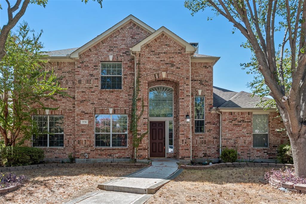 Two-story brick exterior featuring a multi-gabled roofline, an arched entryway with a transom window, and stone hardscaping borders Two-story brick exterior featuring a multi-gabled roofline, an arched entryway with a transom window, and stone hardscaping borders