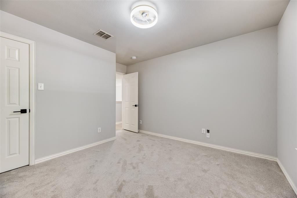 Neutral-toned wall paint, plush carpeting, multi-panel doors with matte black hardware, and a circular flush-mount ceiling fixture