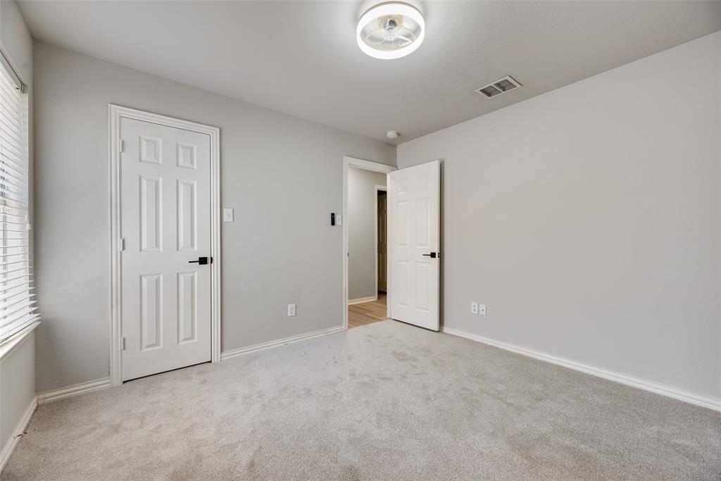 Neutral wall finishes, carpeted flooring, two six-panel interior doors with matte black hardware, and a flush-mount circular LED light fixture