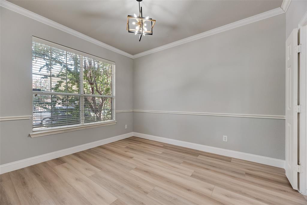 Room featuring wood-finish flooring, crown molding, chair rail trim, large window with neutral blinds, and an industrial-style geometric chandelier