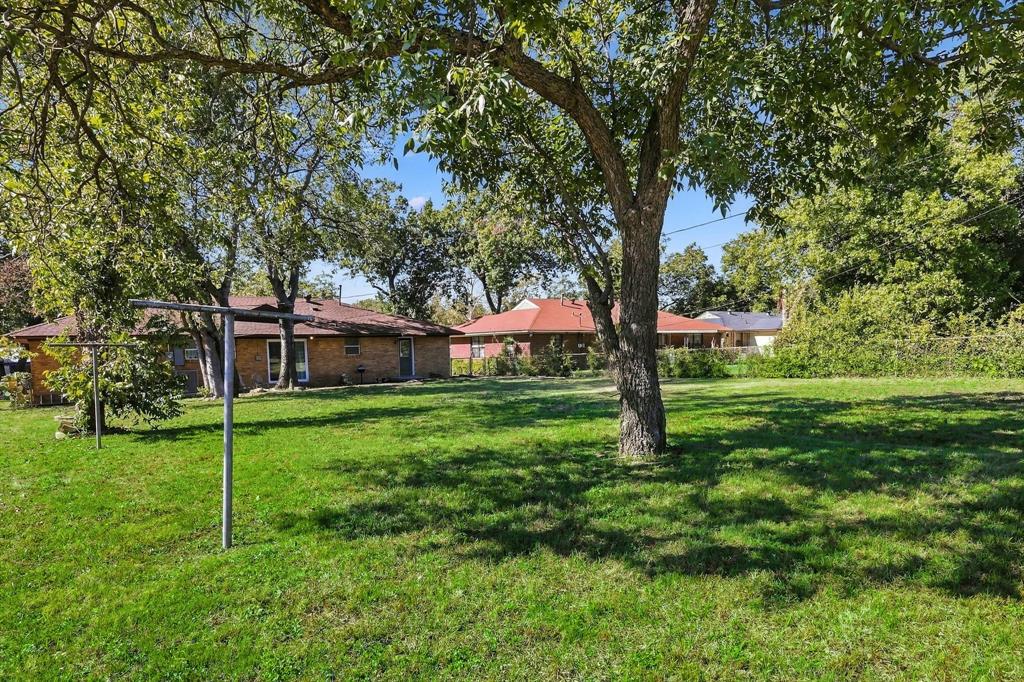 Expansive backyard featuring a sprawling lawn, mature trees, and perimeter fencing