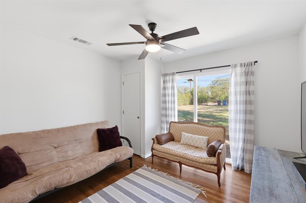 Interior room featuring wood-finish flooring, a ceiling-mounted light fixture with fan blades, and a large window