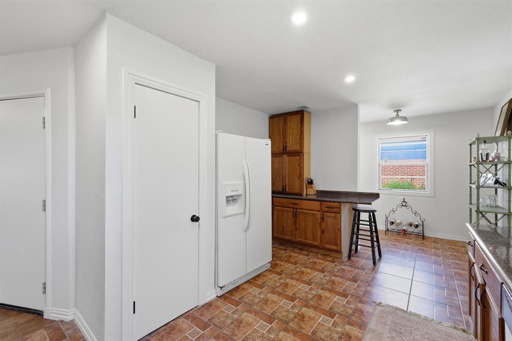 Kitchen featuring wooden cabinetry, dark stone-finish countertops, tile flooring, and recessed ceiling lighting