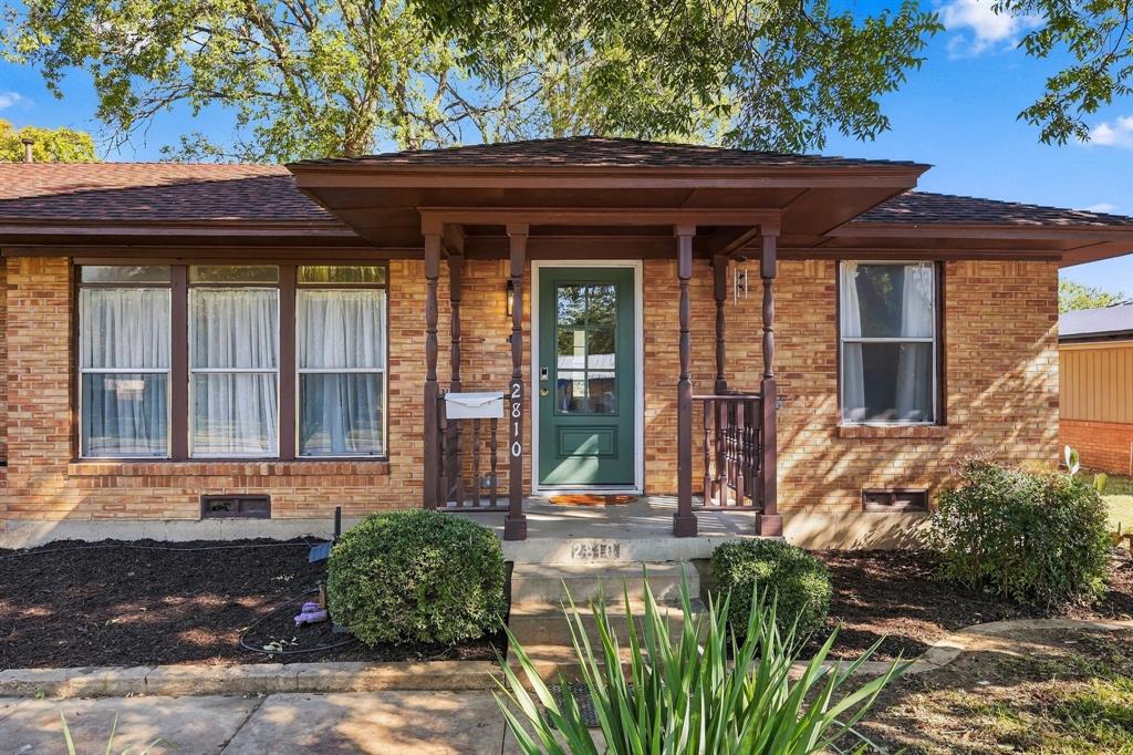 Single-story brick exterior featuring a covered front porch with turned wood columns, a paneled front entry door, and multi-pane windows