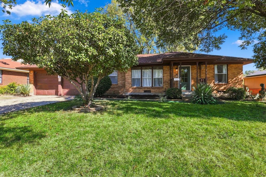 Single-story brick exterior featuring a covered front porch, attached two-car garage, and established landscaping