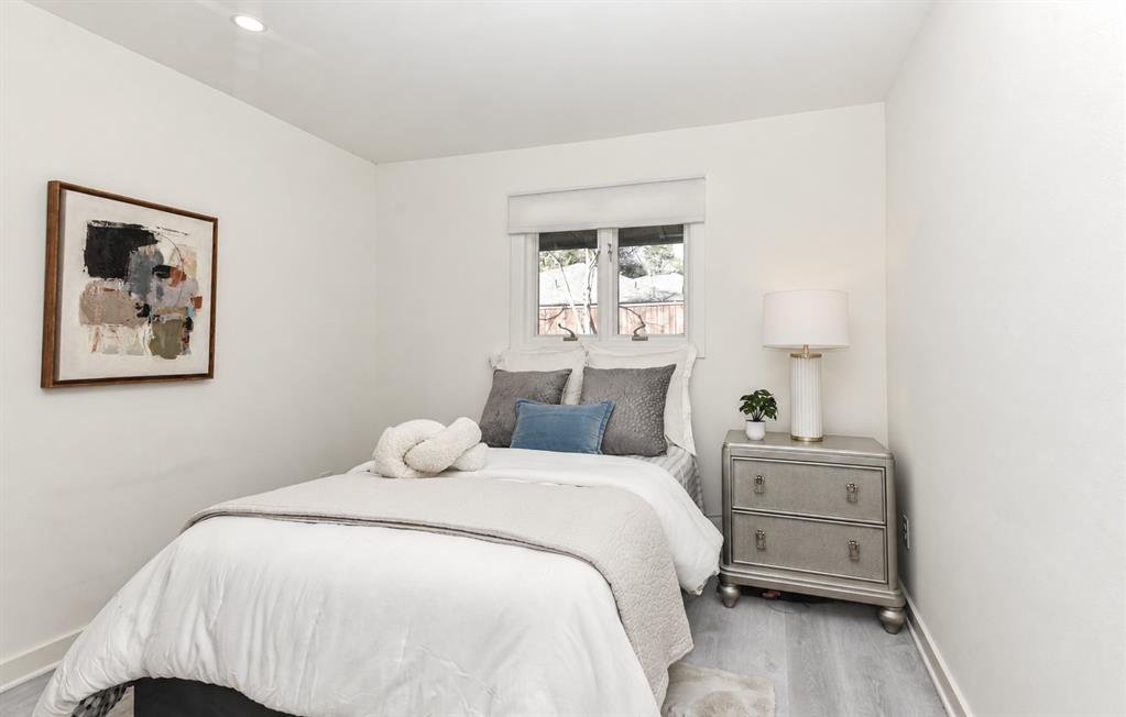 2nd Bedroom has neutral-toned interior featuring wood-finish flooring, recessed lighting, and a dual-pane window with a roller shade