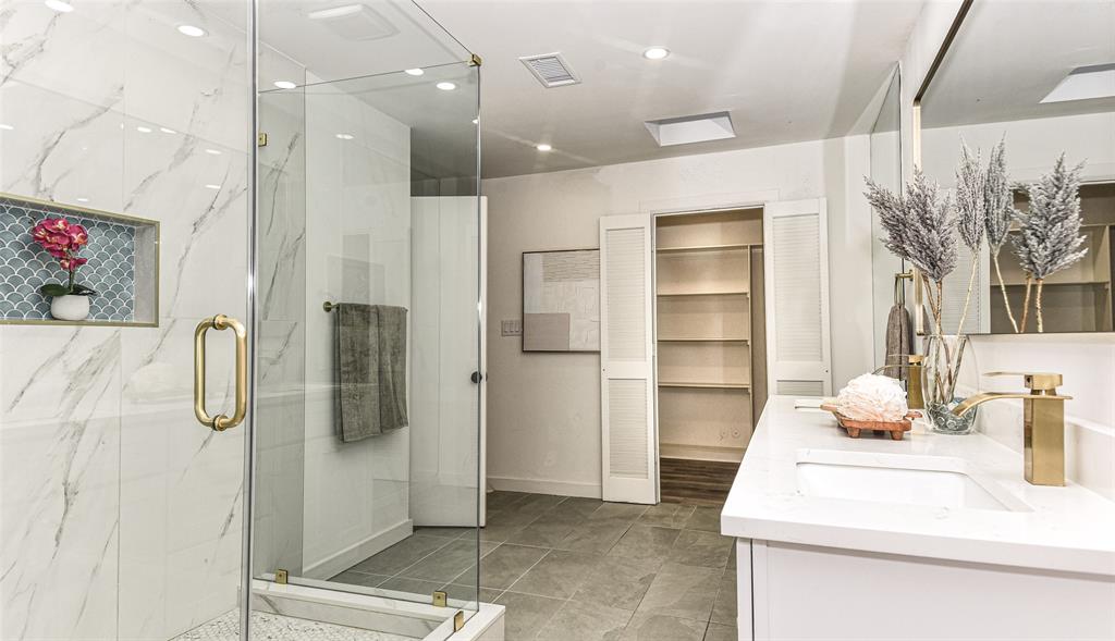 Ensuite Bath to the Primary Bedroom has it all...Walk-in shower with floor-to-ceiling veined tile, glass enclosure, gold-toned hardware, and decorative niche, paired with a dual-sink vanity featuring stone countertops and gold-toned fixtures Ensuite Bath to the Primary Bedroom has it all...Walk-in shower with floor-to-ceiling veined tile, glass enclosure, gold-toned hardware, and decorative niche, paired with a dual-sink vanity featuring stone countertops and gold-toned fixtures