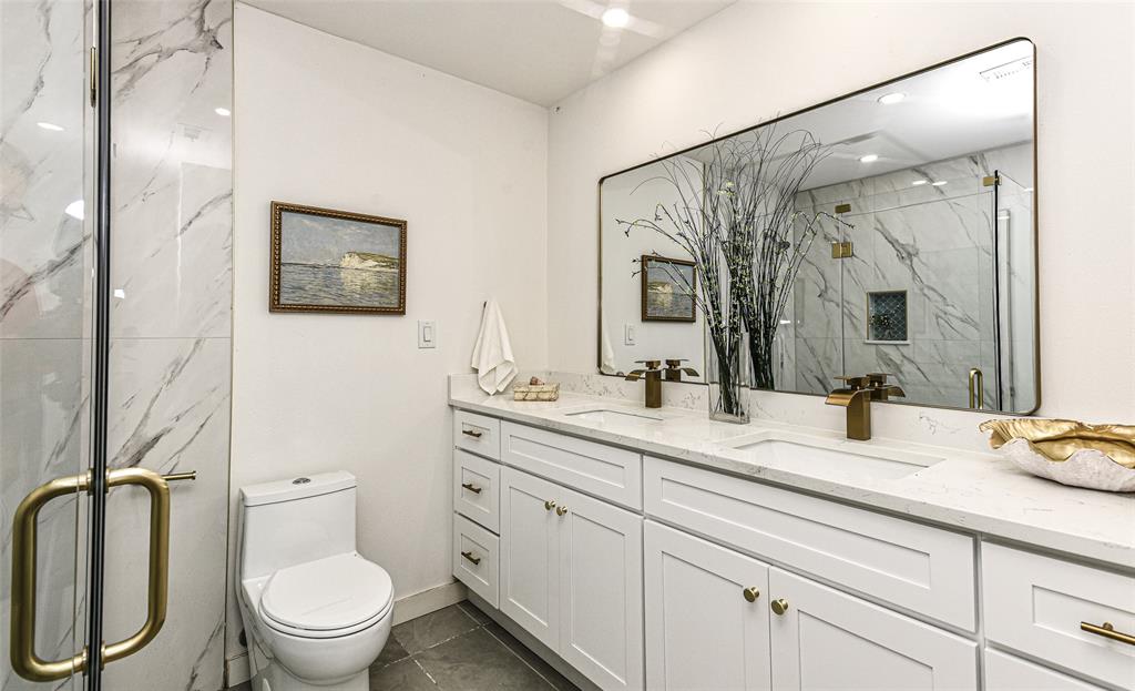 Your Guests will love the Dual-sink vanity with white shaker-style cabinetry, quartz countertop, and brass fixtures, accompanied by a large wall-to-wall mirror and a walk-in shower