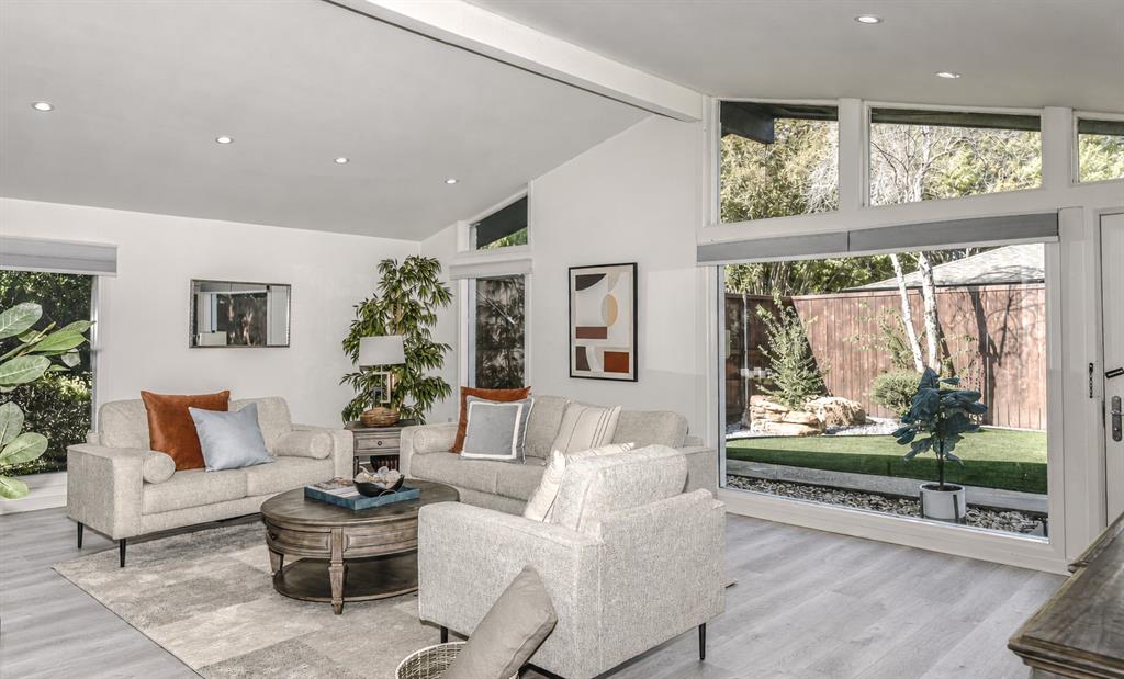 Living area has Vaulted ceiling with recessed lighting, expansive floor-to-ceiling windows, and wood-finish flooring Living area has Vaulted ceiling with recessed lighting, expansive floor-to-ceiling windows, and wood-finish flooring