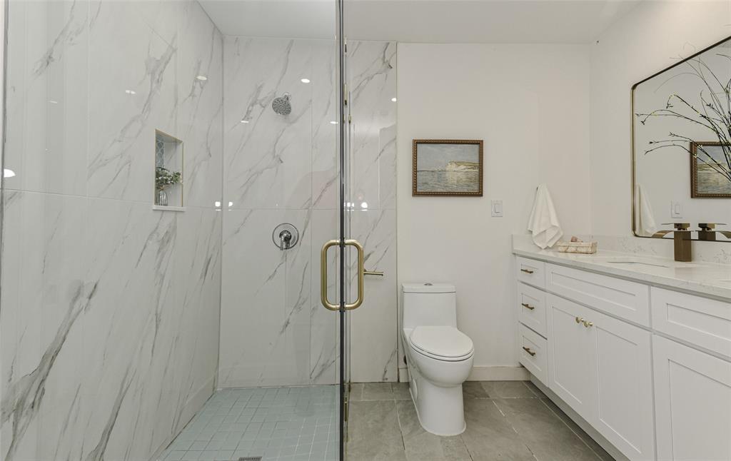 The Walk-in glass-enclosed shower has wall-mounted shower head and integrated recessed niche