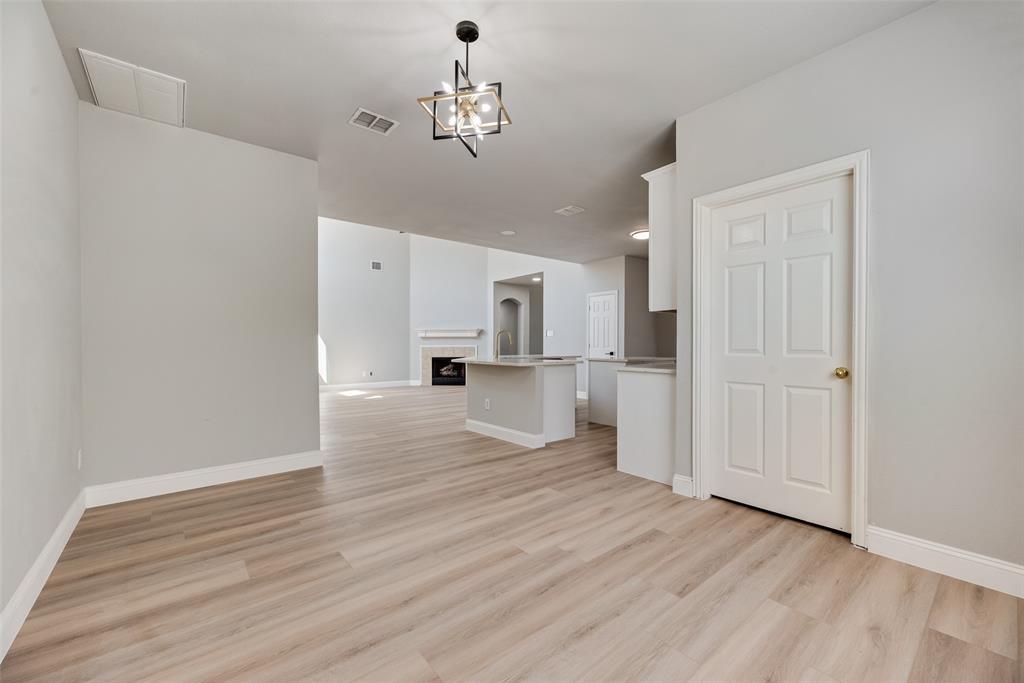 Interior space featuring wood-finish flooring, a geometric pendant light fixture, a neutral color palette, a kitchen island, and a fireplace