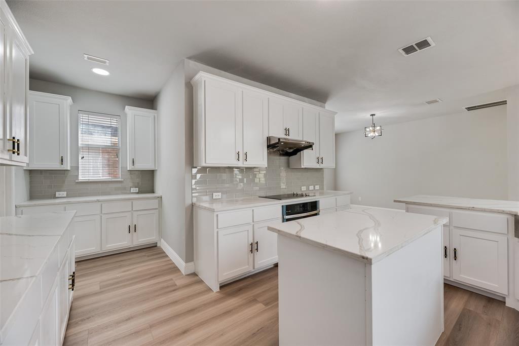 Kitchen featuring white cabinetry, center island with stone-finish countertops, subway tile backsplash, and wood-finish flooring