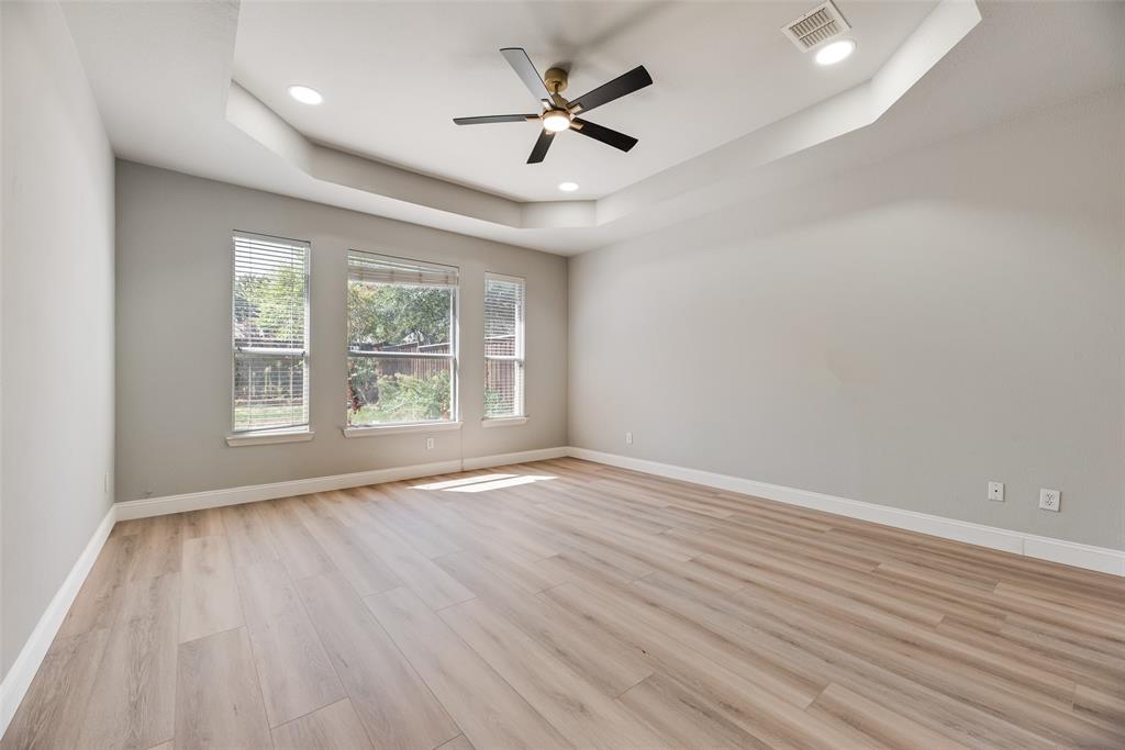 Room featuring a tray ceiling, wood-finish flooring, recessed lighting, and a multi-blade ceiling fan with an integrated light fixture