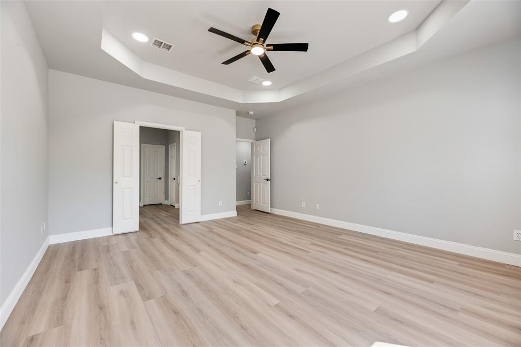 Tray ceiling with recessed lighting, wood-finish flooring, and a central ceiling fan with integrated light fixture