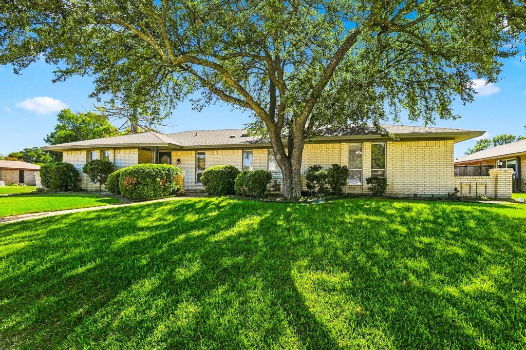 Single-story exterior featuring light-toned masonry, a low-profile roofline, mature trees, and manicured landscaping Single-story exterior featuring light-toned masonry, a low-profile roofline, mature trees, and manicured landscaping
