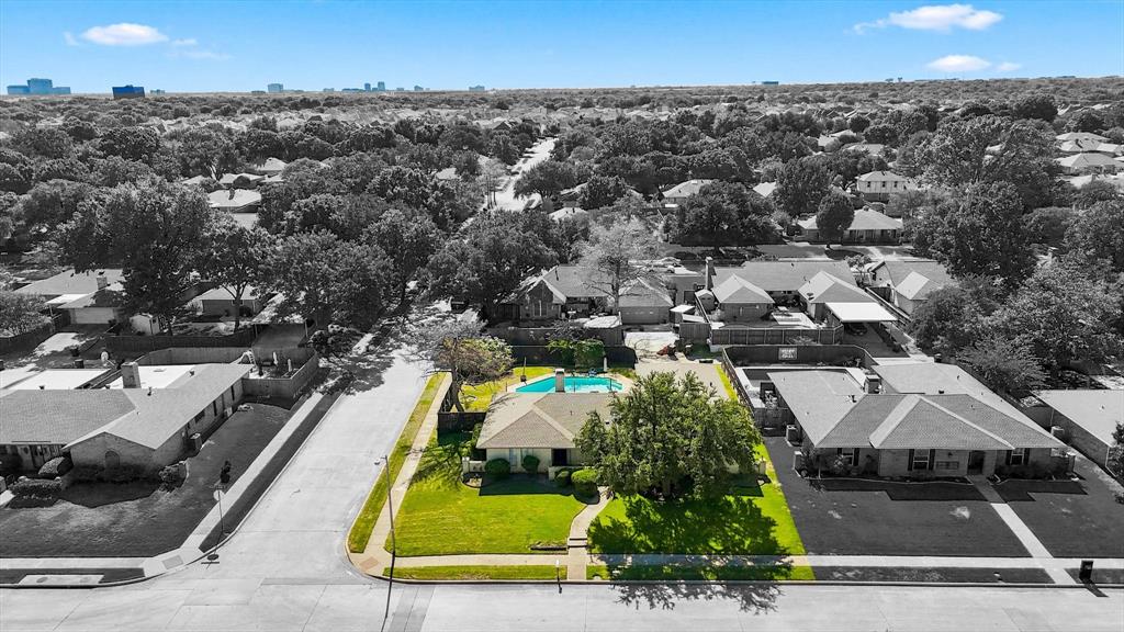 Aerial perspective featuring a single-story residence on a corner lot with an inground pool and mature landscaping