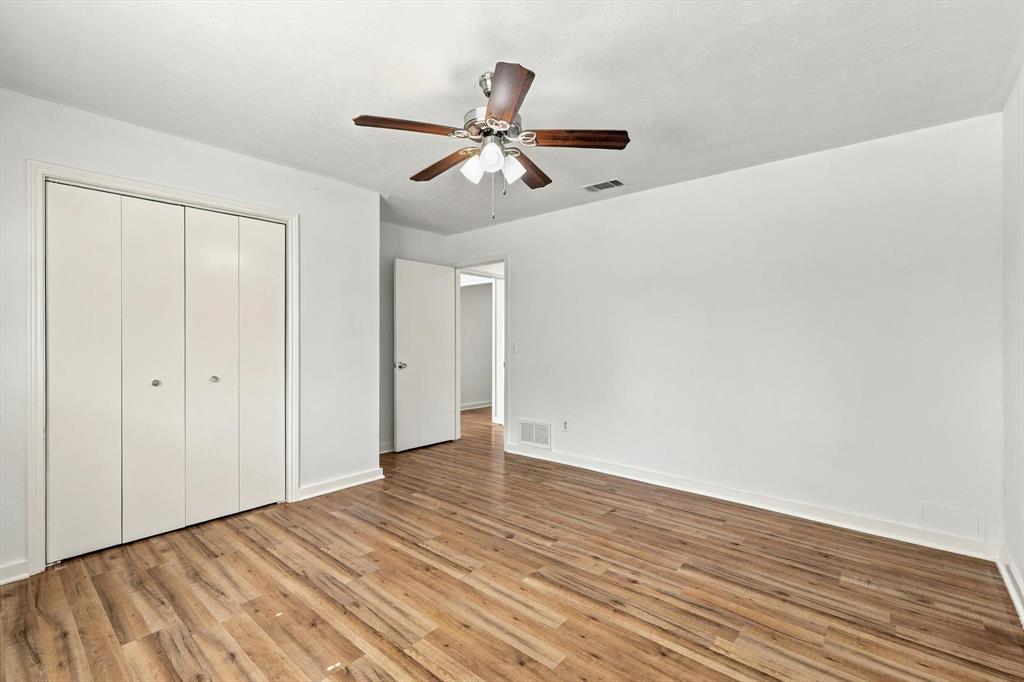 Interior room featuring wood-finish flooring, a multi-panel closet, and a ceiling fan with integrated lighting