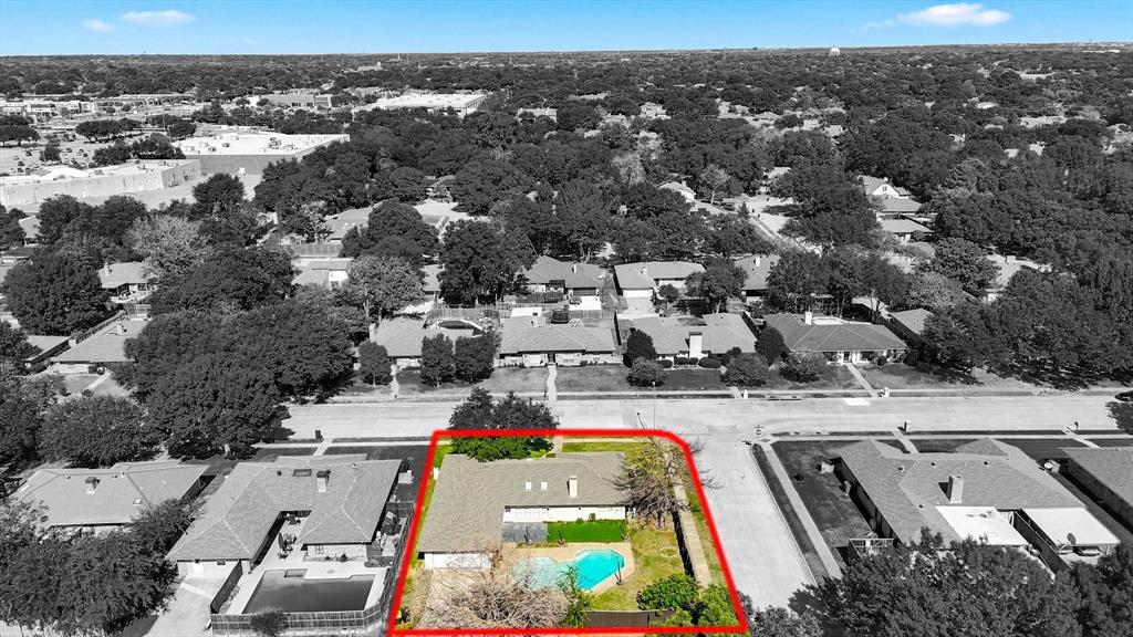 Aerial view of property featuring a corner lot, a swimming pool, and mature trees