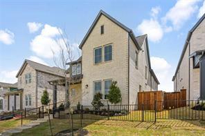 Two-story masonry exterior featuring light-toned brick cladding, multi-pane windows, a steep roofline, and a black metal perimeter fence