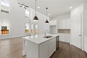 Kitchen featuring a center island with quartz countertop, high-reach vaulted ceilings, recessed lighting, pendant light fixtures, and wood-finish flooring